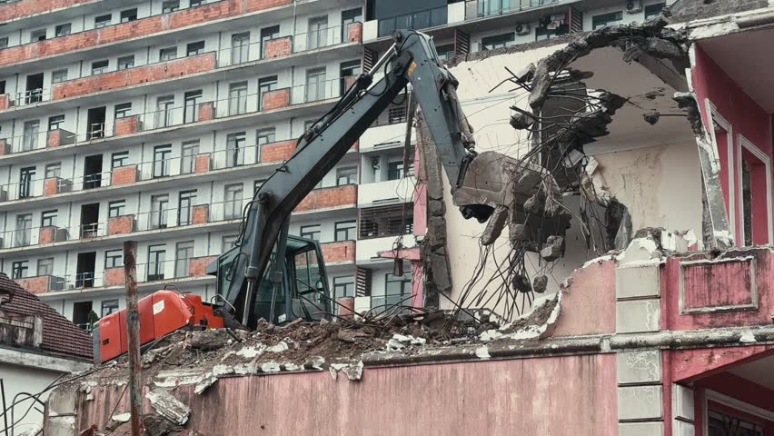 Excavator demolish or remove old ruined building in rainy day. Old house demolition on construct cite for renovation new housing in modern city