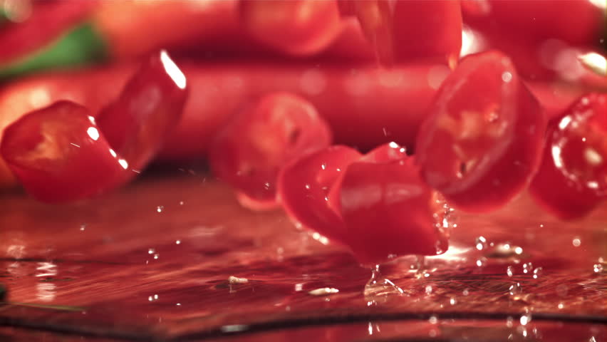 Sliced chili pepper pieces fall on a cutting board. Filmed on a high-speed camera at 1000 fps. High quality FullHD footage