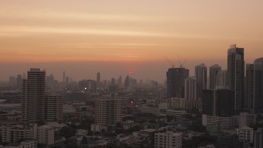 The sun sets amidst the density of buildings and the hustle and bustle of Bangkok city