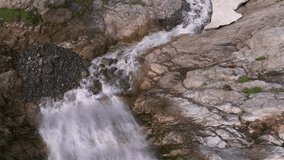Aerial view of a glacial waterfall high in the mountains on a sunny day. Close up of a tall waterfall