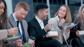 Group of international businesspeople eating lunch at city street outside of the office. - Powered by Shutterstock - Get 15% off with code: PIKWIZARD15