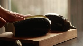 precise preparation: woman hands cutting eggplant into cubes on wooden board close-up