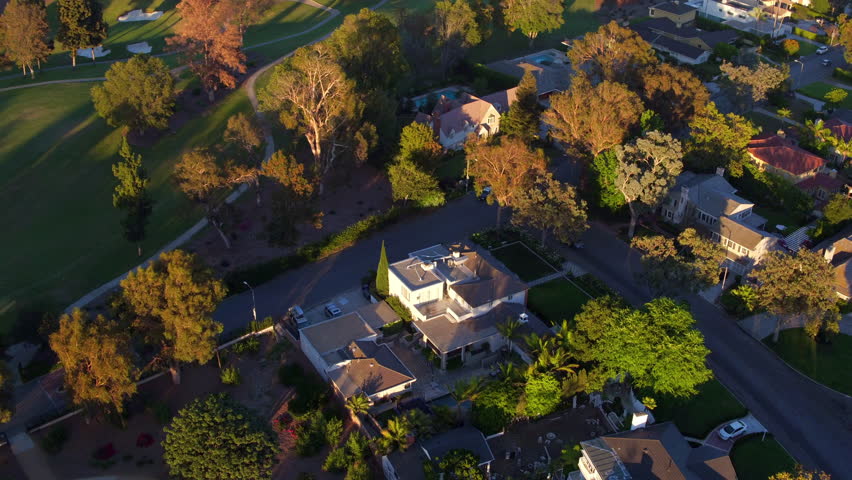Aerial Panning Shot Of Roofed Houses And Golf Courses On Green Landscape - Long Beach, California