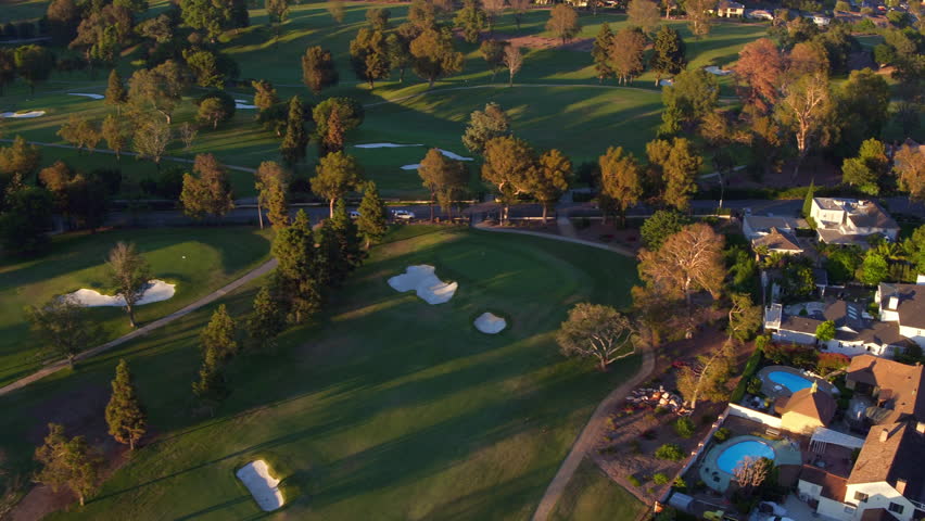 Aerial Panning Shot Of Green Golf Courses On Residential City Landscape During Sunny Day - Long Beach, California