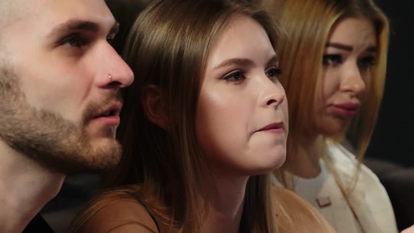 Woman laughs holding controller between man and female friend. Young enthusiasts intensify to collaborate to overcome in-game obstacles