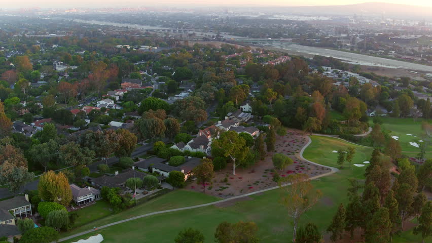 Aerial Panning Beautiful Shot Of Houses And Green Golf Course In City At Sunset - Long Beach, California