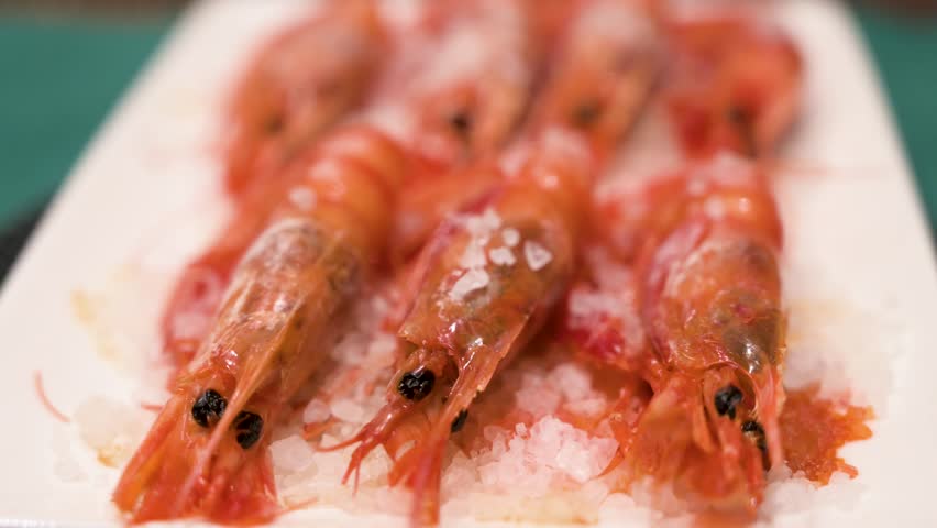 Homemade oven-cooked seafood red shrimp dish on a pristine white platter and garnished with a sprinkle of sea salt.