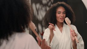 Happy active African American woman girl with curly hair in bathroom pointing in mirror reflection singing song in bath brush sing dancing having fun in morning beauty routine enjoy pampering hygiene - Powered by Shutterstock - Get 15% off with code: PIKWIZARD15