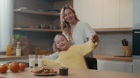 Happy carefree smiling mother and little daughter at kitchen having fun hold hands dancing to music moving dance mom with child girl hug kid hugging embracing cuddling family breakfast love bonding - Powered by Shutterstock - Get 15% off with code: PIKWIZARD15