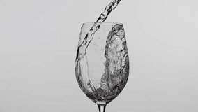 Close up studio shot of goblet in drops isolated on white background in studio. White wine or water pouring into a wine glass from the bottle creating wave. - Powered by Shutterstock - Get 15% off with code: PIKWIZARD15