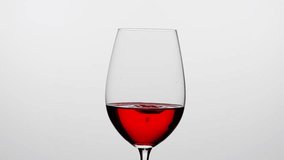 Studio shot of beautiful goblet isolated on white background in studio. Wine glass filled with red wine, drops falling inside creating ripples. - Powered by Shutterstock - Get 15% off with code: PIKWIZARD15