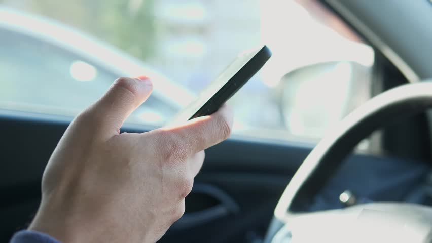 The driver uses his smartphone while driving to send messages, chat with friends and read the news. Royalty-Free Stock Footage #3427155663