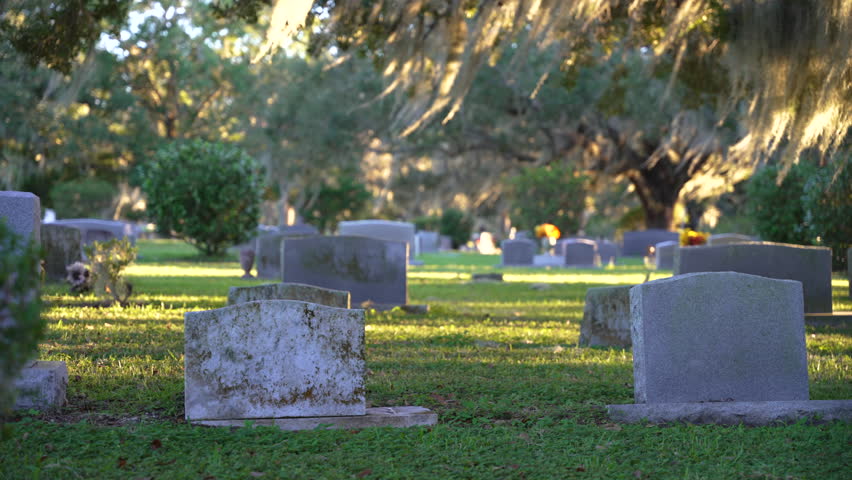 Old American cemetery with rows of tombstones under southern oak trees on green grass in Orlando, Florida Royalty-Free Stock Footage #3427196109
