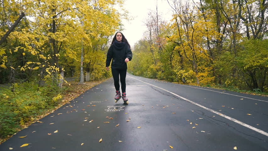 Young Woman On Roller Skates among beautiful autumn trees