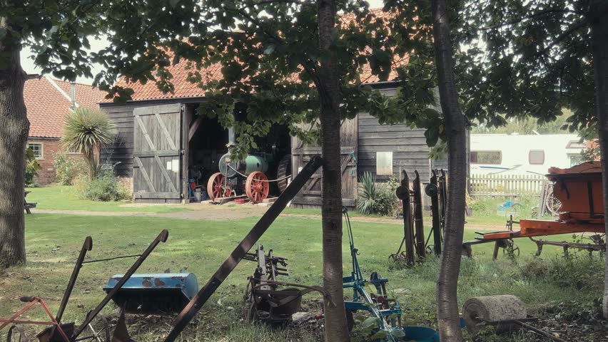Old vintage historical farm machinery equipment sitting around in a farmers field. Retro 70s movie effects