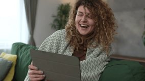 One caucasian woman with curly hair sit at home use digital tablet to watch movie or series online stream or to have video call happy smile have a good time slow motion - Powered by Shutterstock - Get 15% off with code: PIKWIZARD15