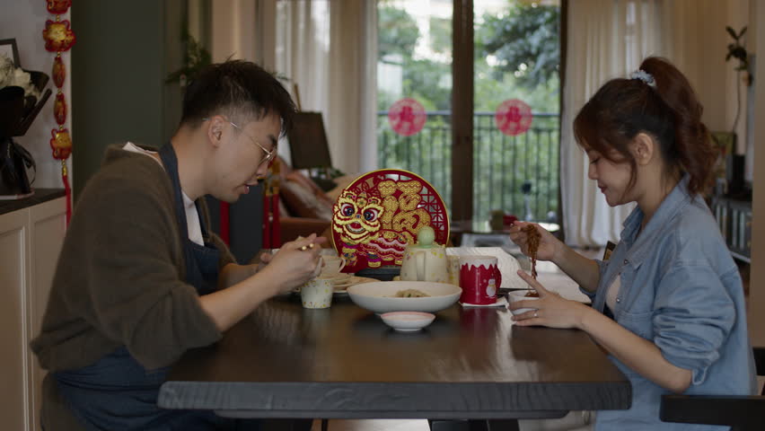 Chinese New Year happy couple sitting at home celebrating the event while eating traditional asiatic food Royalty-Free Stock Footage #3427300211