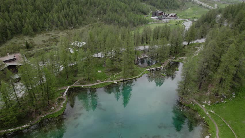 Establishing shot over Lake Blu, tilting up towards cloud-covered Matterhorn