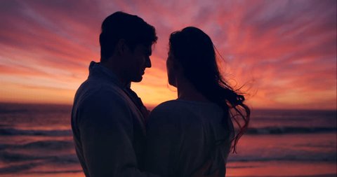 Silhouette, beach and couple at sunset kiss for bonding, together and relationship by ocean. Dating, nature and man and woman with affection and love for romance on holiday, vacation and weekend – Stockvideo