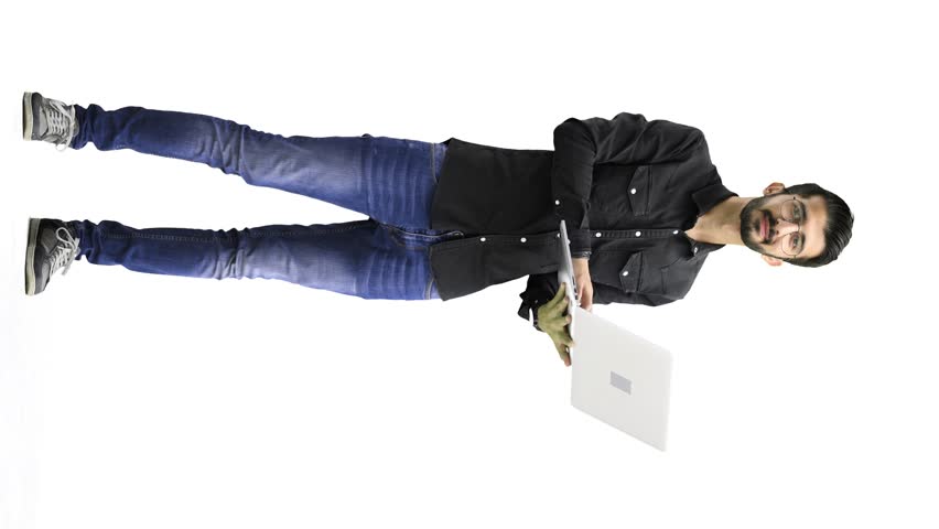 A man, on a white background, in full height, uses a laptop