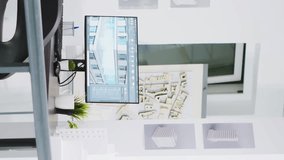 Vertical Video Cad modeling system running on PC at a empty workstation, urbanistic designs and layouts on table. Innovative architectural creative business desktops equipped with manufacturing tools.