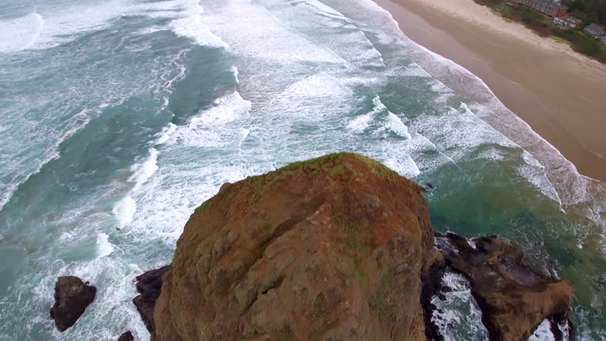 Aerial Tilt Up Shot Of Famous Haystack Rock In Wavy Sea At Beach Under Cloudy Sky - Cannon Beach, Oregon Royalty-Free Stock Footage #3427439751