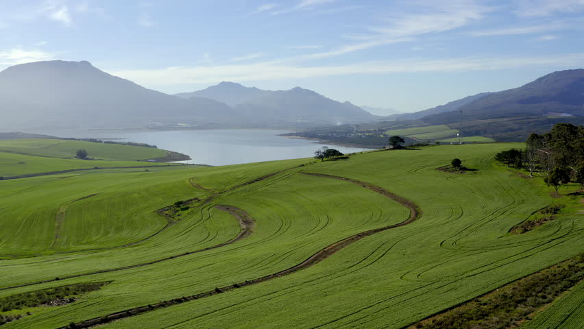 Drone, mountains and countryside with lake, landscape and outdoor growth, ecology or environment. Aerial, hill and field for agriculture, water or plants in sunshine for sustainability in Cape Town