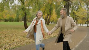 Funny romantic old couple having fun in autumn park smiling mature woman and man happy family dancing together outdoors enjoying holding hands jumping feeling happiness dance active retirement in city - Powered by Shutterstock - Get 15% off with code: PIKWIZARD15