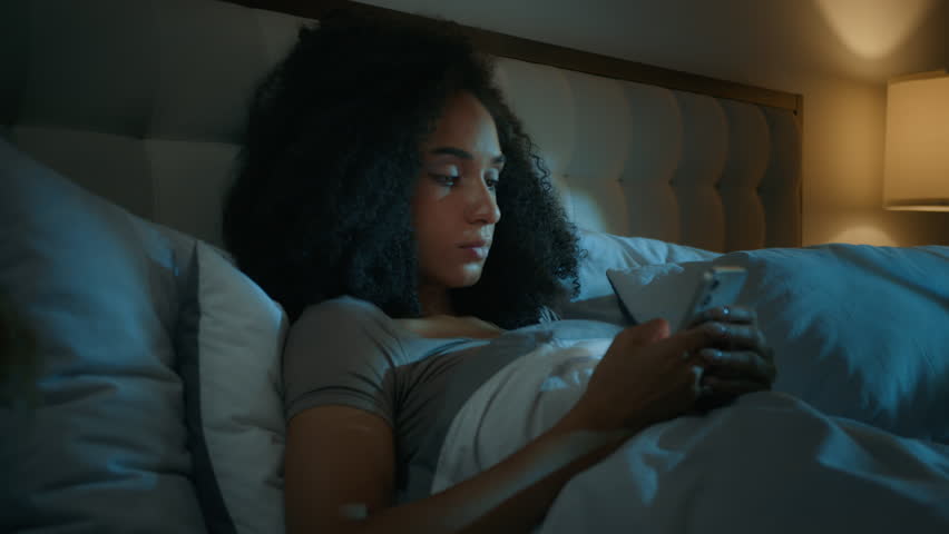 African American girl scrolling smartphone mobile phone online apps in bed before sleeping upset shocked ethnic woman customer worried internet problem loss connection error mistake bad news rejection Royalty-Free Stock Footage #3427449191