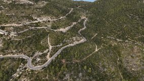 Drone shot of driving cars on the winding road in the Esporles valley on the island village of Mallorca in the Serra de Tramuntana, Spain
