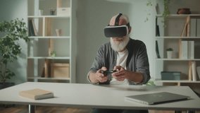 An Old Man in VR Glasses Plays Computer Games With a Joystick, Sitting at the table.A Modern Elderly Man Plays PlayStation. Augmented Reality and Gaming for Seniors. - Powered by Shutterstock - Get 15% off with code: PIKWIZARD15