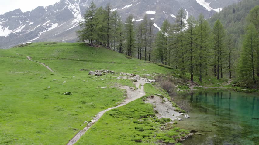 Hiking trail along lakeside of Lago Blu reflecting the fir trees