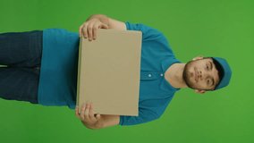 Vertical Video Green Screen Portrait of Handsome Delivery Person in Uniform Holds Cardboard Boxes and Smiles. Courier Working in Logistics Distribution Center, Delivering Online Orders.