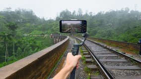 Shooting of trip on tripod phone. Action. Blogger professionally shoots videos on phone while traveling. Beautiful shooting on your phone in tropical jungle