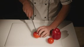 Chef cutting up a tomato with a knife. slow motion