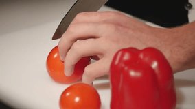 Chef cutting up a tomato with a knife. close up