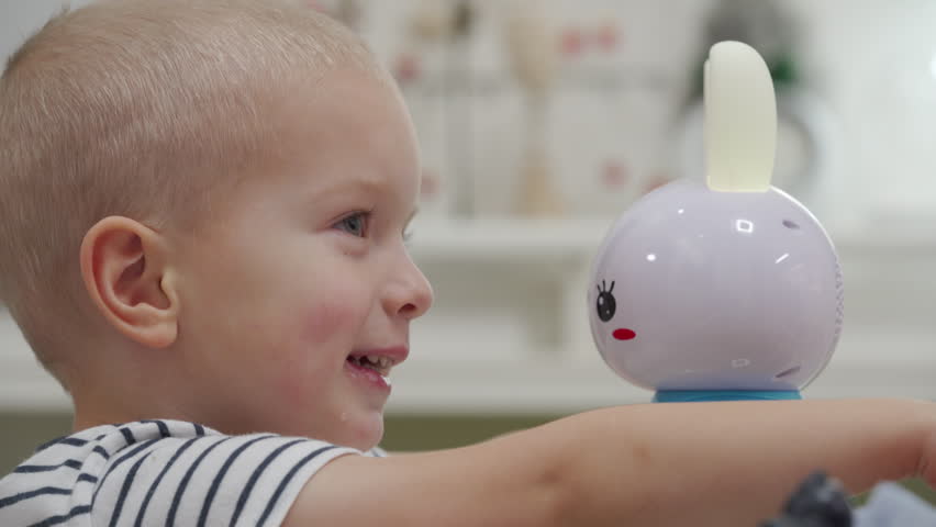 Happy little boy playing with baby recording repeats musical toy. Electronic interactive rabbit musical bunny toy.