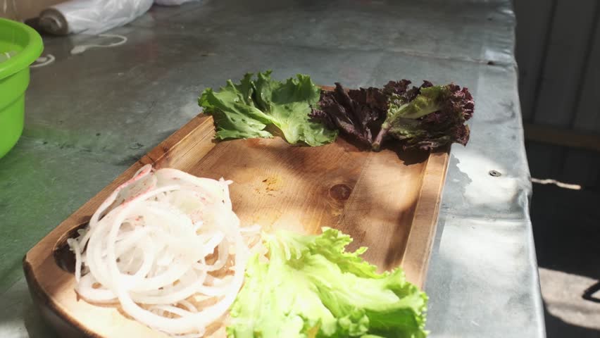 The chef serves kebabs with chicken, cape and liver on a wooden board with onions, herbs, tomatoes and vegetables.