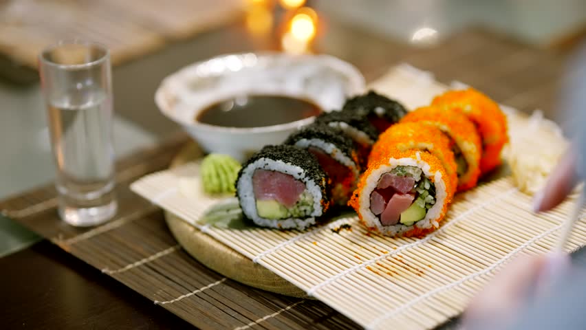 Chopsticks Take Japan Sushi In Japanese Restaurant.Traditional Sushi Maki Rolls Sushi Salmon Philadelphia Cheese Avocado, Cucumber, Rice And Nori. Japanese Food Sushi Roll Uramaki, Nigiri And Hosomaki