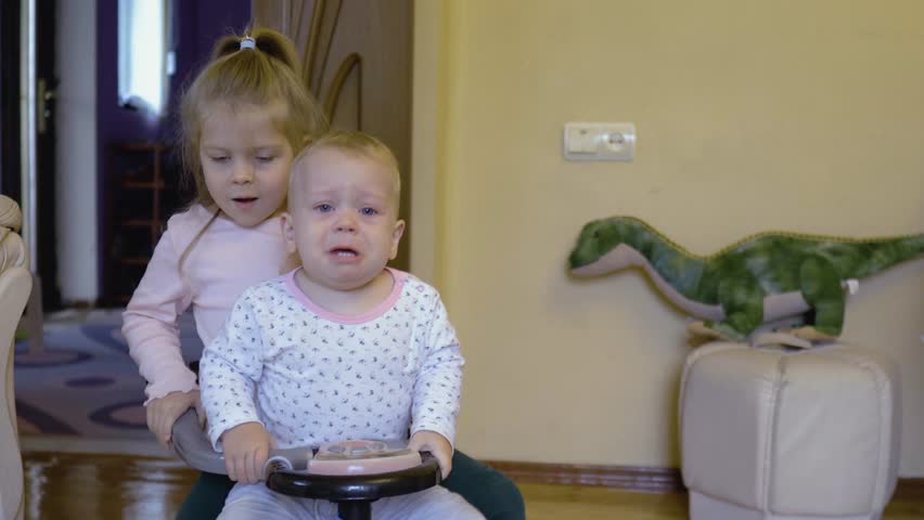 Toddler crying bitterly, two caucasian children sitting next to each other