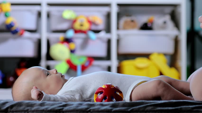 Young mother talks and plays with her baby son while lying on her back. Baby care, motherhood concept.