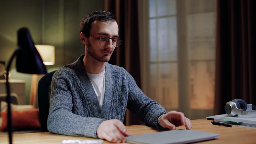Caucasian male student opening laptop for passing exam online on modern gadget while staying at home. Man young freelancer works in living room. Concept of people, distance learning and technology. Royalty-Free Stock Footage #3427844297