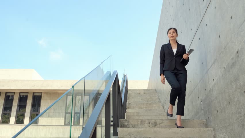 Confident successful business woman walking down stairs in an unhurried and relaxed way.