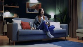 Young beautiful woman watching fun movie on television at home. Attractive casual girl feel happy and relax, sitting on sofa having fun watch comedy video on TV in house. Activity lifestyles concept.