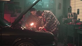 Maintenance service and small family business. Inspection of engine and checking motor oil level. Young boy helps father repair broken car engine in home garage. Dad and son spending time together. - Powered by Shutterstock - Get 15% off with code: PIKWIZARD15