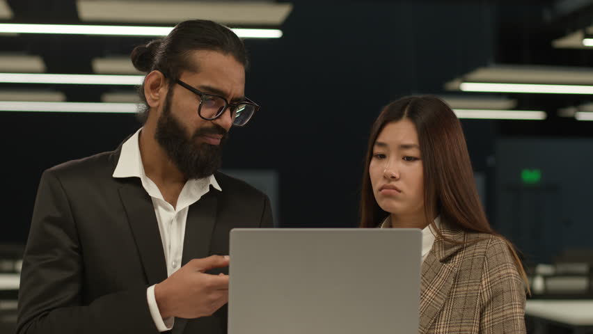 Indian businessman boss leader reprimanding Korean female Asian sad upset worker woman failure showing online mistake bad work result dissatisfied with laptop talk office diverse business colleagues Royalty-Free Stock Footage #3427995507