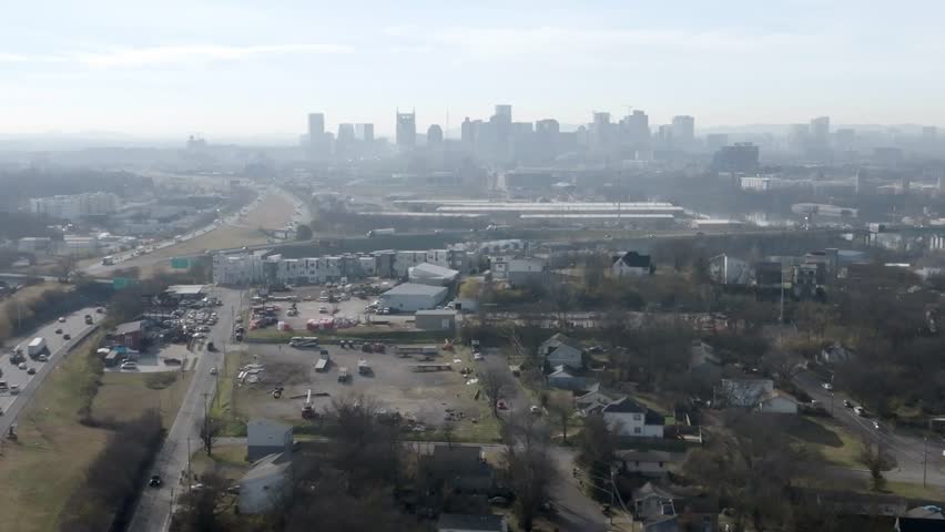 Nashville, Tennessee skyline wide shot with freeway traffic moving sideways.
