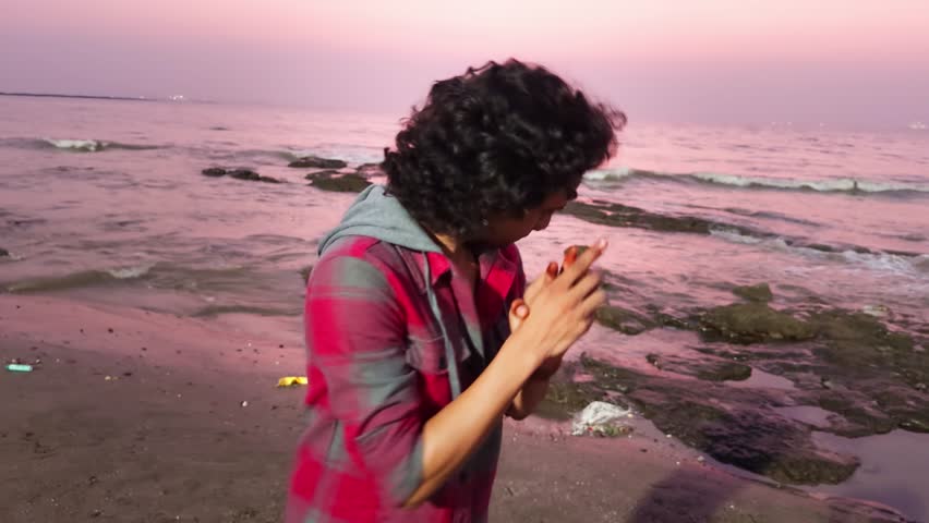 Young man standing talking giving speech having conversation on a beach at sunset asian male