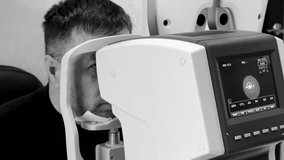 A middle aged man conduct an eye examination in an ophthalmology office black and white video