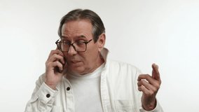 An elderly man enjoys a light-hearted moment during a phone conversation, laughing joyfully with someone on the other end, dressed casually in a light jacket and glasses. Camera 8K RAW. 